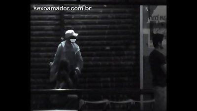 Mulher faz sexo oral no parceiro, em parada de &ocirc;nibus na rua